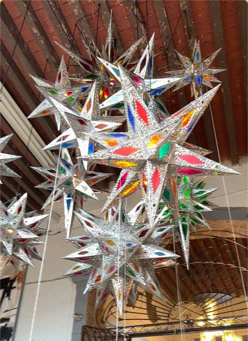 Tin and colored glass star lanterns hanging in the gallery